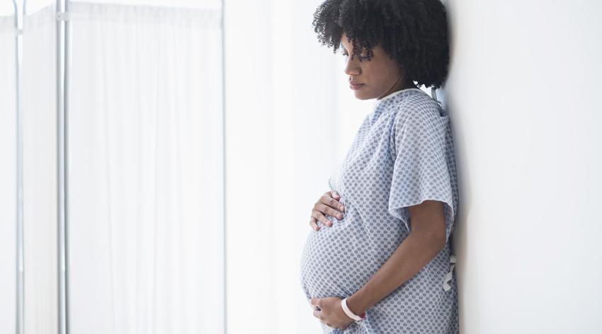 Pregnant African American mother holding stomach in hospital