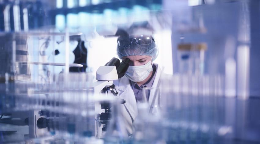 Female microbiologist studying coronavirus with microscope