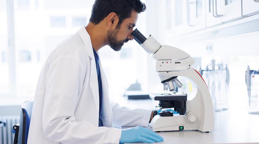 Scientist in laboratory looking into microscope