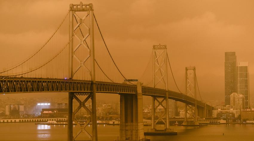 Smoke from wildfires in California covers the San Francisco - Oakland Bay Bridge and buildings on the San Francisco skyline.