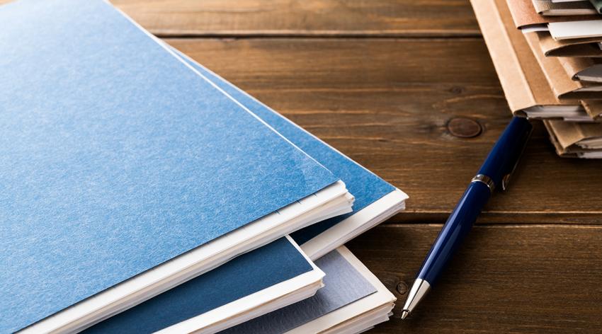 A pen and two stacks of paperwork on office desk table