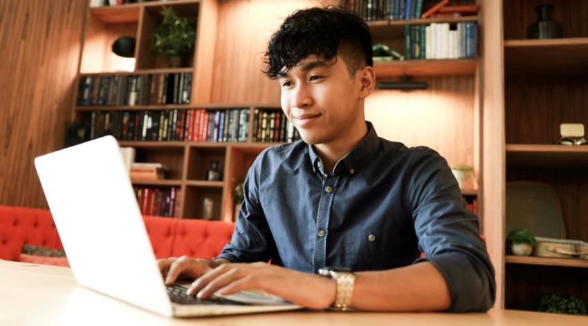 Young asian student is working on laptop in the library