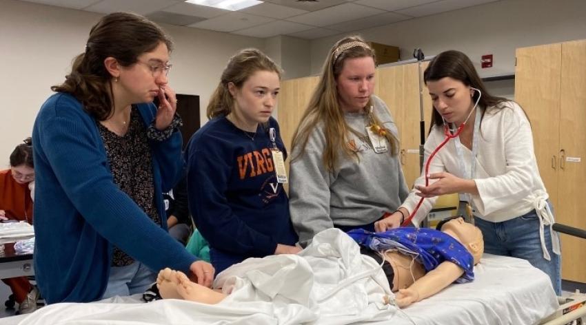 Students gathered around a hospital bed practicing evaluating patients