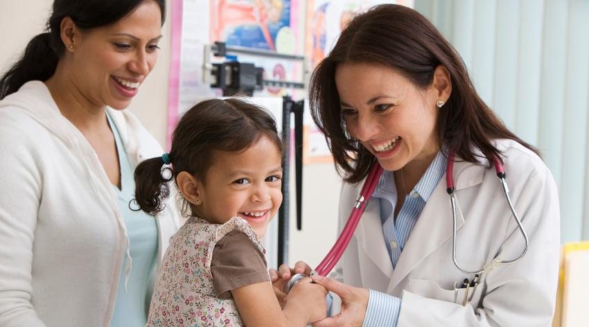 Toddler girl laughing while doctor examines