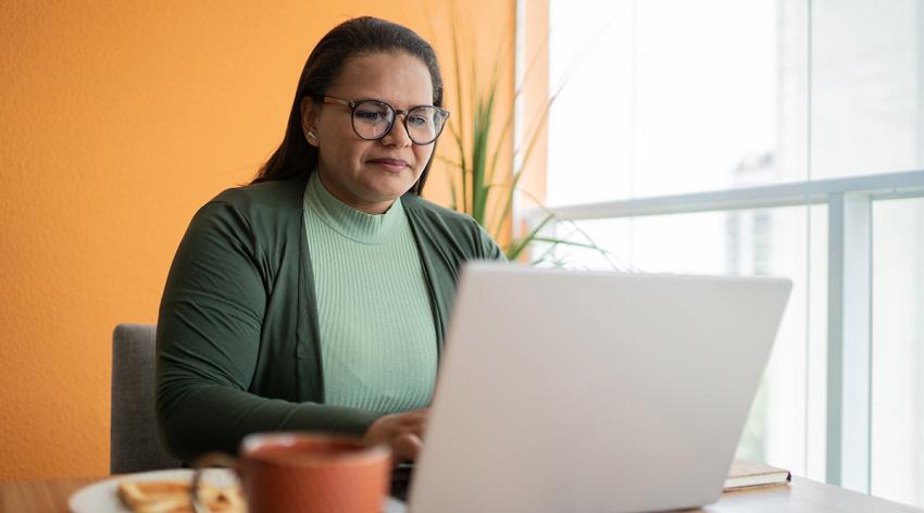 Mature woman using laptop in apartment's balcony