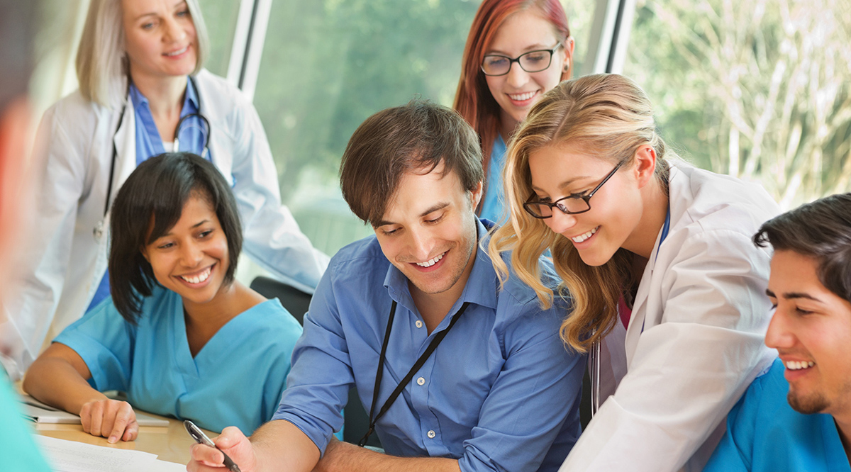 Medical residents sitting around a table reviewing a document. 