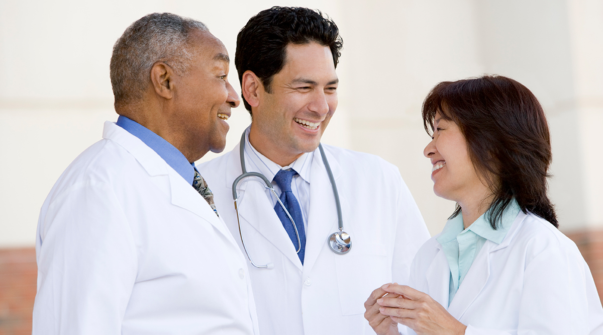 Three doctors standing outside a hospital