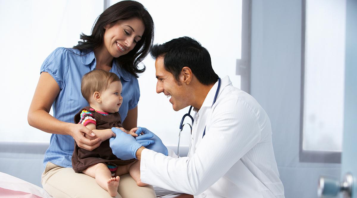 Doctor examining baby girl with mother smiling Doctor examining baby girl with mother smiling