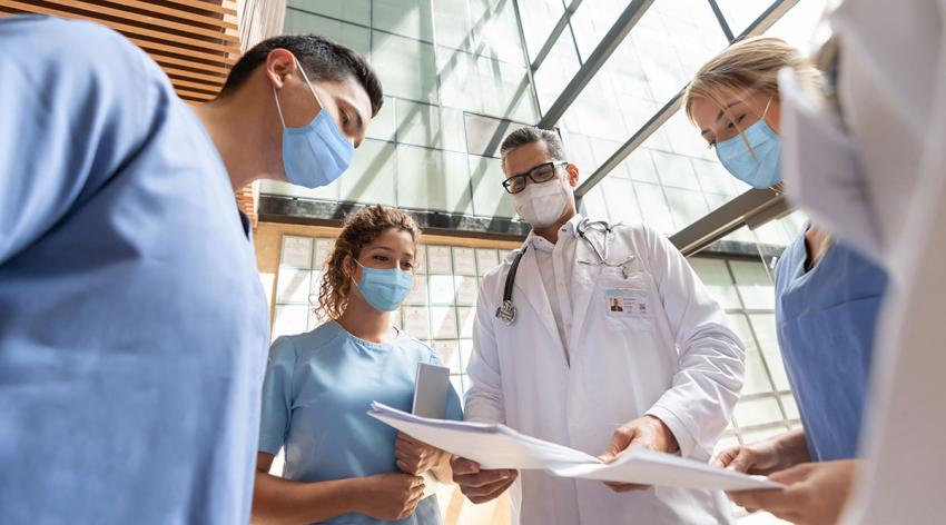 Group of doctors talking at the hospital and wearing facemasks