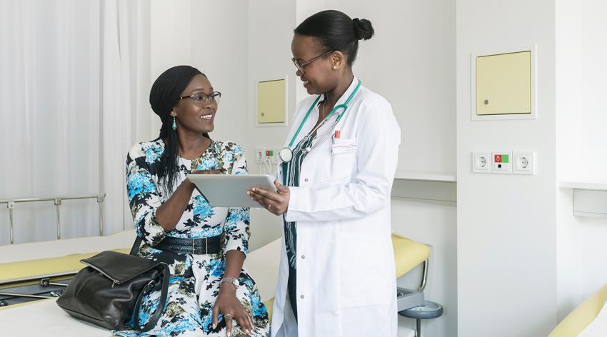 Female doctor discussing medical test results with mature patient using digital tablet